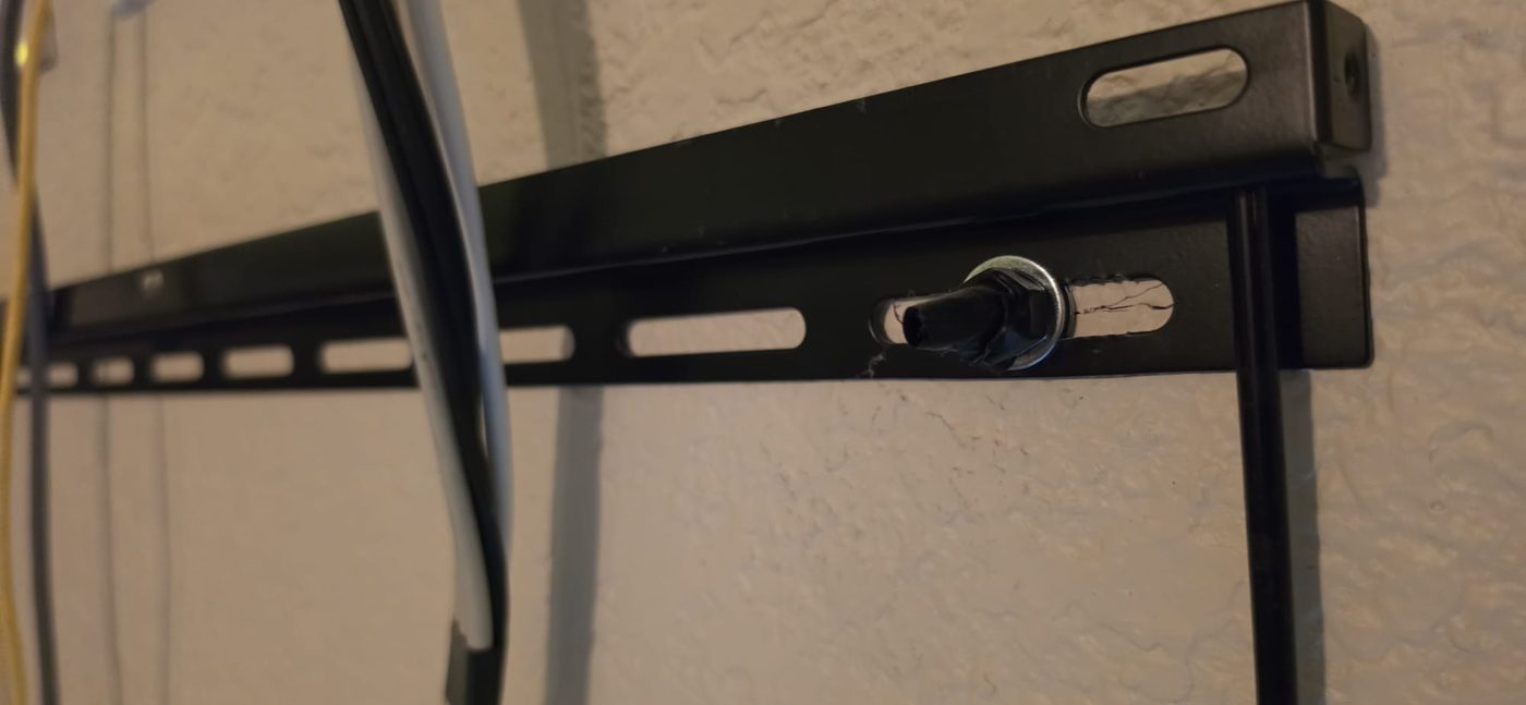 A mount bolt set in a plastic drywall anchor, with the wall already cracking around it